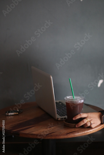 A cup of amaricano and laptop on the wood table photo