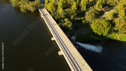 One person in a bicycle crossing bridge of river dam, Cordoba in Argentina. Aerial.