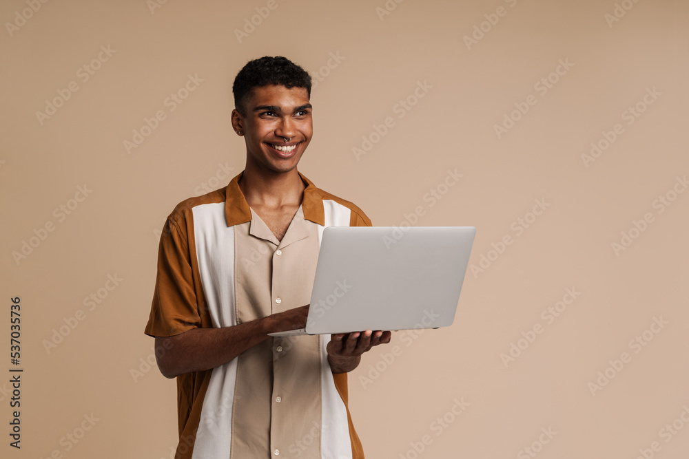 Young handsome smiling african man with piercing holding laptop Young handsome smiling african man with piercing holding laptop