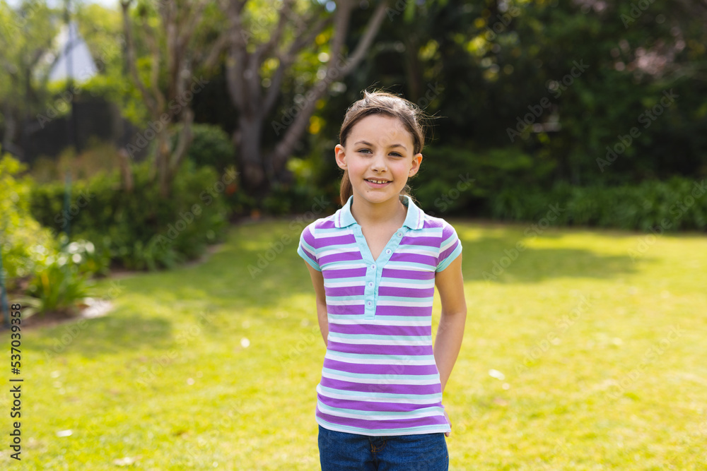 Portrait of young caucasian girl wearing striped t-shirt and standing in the garden Portrait of young caucasian girl wearing striped t-shirt and standing in the garden
