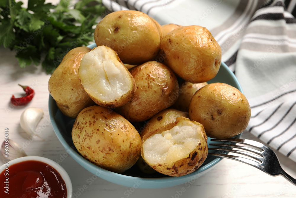 Bowl of tasty whole baked potatoes and sauce on white table, closeup Bowl of tasty whole baked potatoes and sauce on white table, closeup
