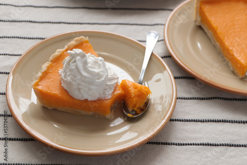 Fresh homemade pumpkin pie with whipped cream on table