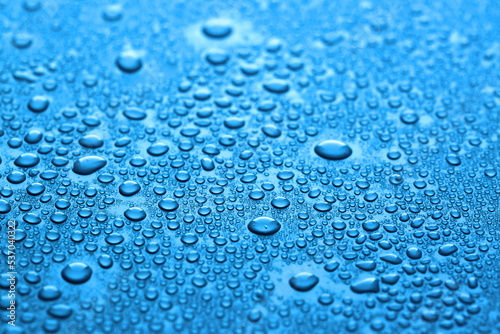 Many water drops on dark dusty blue background, closeup