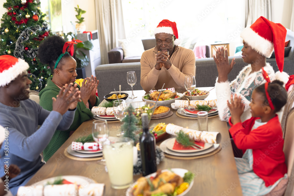 African american family spending time together and praying before having christmas meal