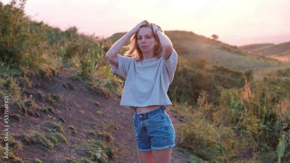 beautiful young woman turns around in the mountains at sunset beautiful young woman turns around in the mountains at sunset