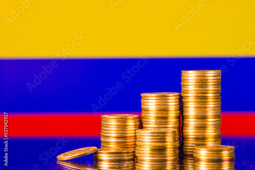 A stack of gold coins on the background of the flag of Colombia . Country economy concept