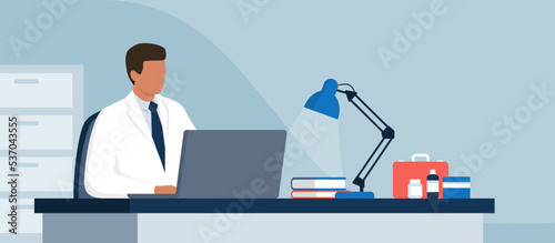 Doctor sitting at desk and working with a laptop