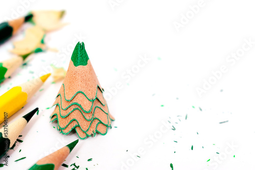 Colored pencils and creative Christmas tree made of shavings from a green pencil.Christmas and New Year flat lay on a white background.Copy space for text.
