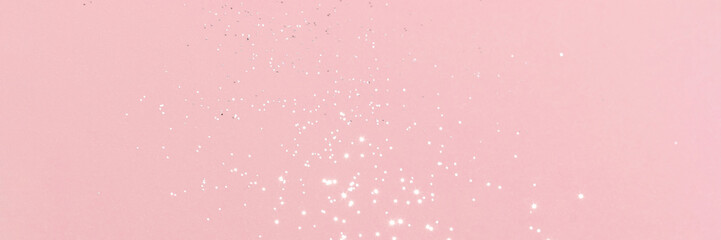 Sparkling silver glitter on pink background banner texture. Abstract holiday blurred lights header. Wide screen wallpaper. Panoramic web banner with copy space for design