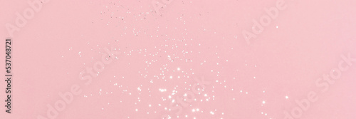Sparkling silver glitter on pink background banner texture. Abstract holiday blurred lights header. Wide screen wallpaper. Panoramic web banner with copy space for design