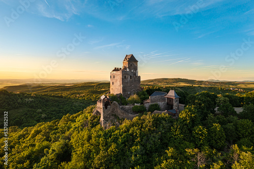 Renewed historical monument in Hungary Mountains. Aerial landscape photo about a medieval castle ruins near by Holloko town. Panoramic landscape photo with forest and amazing sunset photo