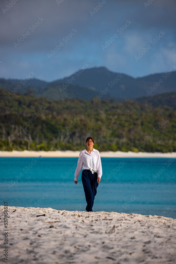beautiful girl in white shirt walks whitehaven beach at sunrise; relaxing on paradise beaches in whitsunday islands, queensland, australia beautiful girl in white shirt walks whitehaven beach at sunrise; relaxing on paradise beaches in whitsunday islands, queensland, australia