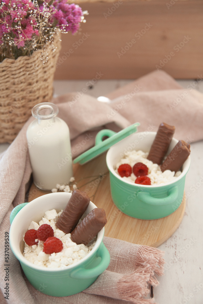 A delicious breakfast of cottage cheese, raspberries, milk and chocolate bars