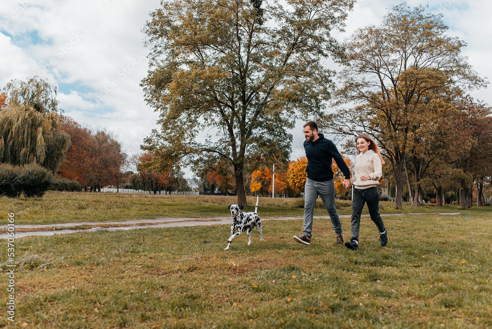 A loving couple plays with a Dalmatian dog on the street. A loving couple plays with a Dalmatian dog on the street.