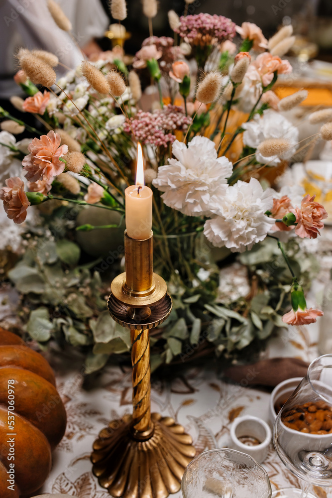 Autumn Decoration and serving of the festive table with autumn decor, candles and flowers and pumpkins.