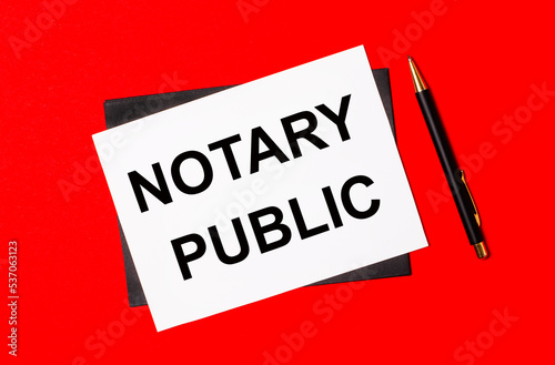 Black pen, envelope and white card with the text NOTARY PUBLIC on a bright red background