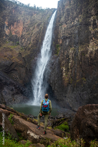 a lone hiker backpacker stands beneath australia's largest waterfall, wallaman falls in queensland