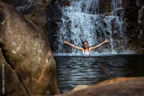 a beautiful girl in a white bikini swims in a natural pool in jourama falls; relaxing in paluma range national park in queensland, australia; cascading waterfalls with pools photo