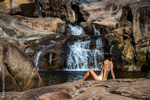 a beautiful girl in a white bikini swims in a natural pool in jourama falls; relaxing in paluma range national park in queensland, australia; cascading waterfalls with pools photo