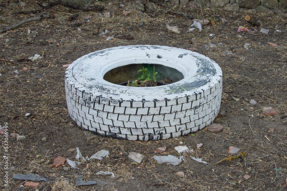 a bad old tire painted white lying on the dirt floor