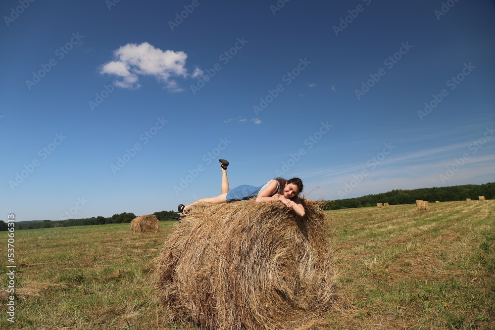 girl resting in a field on a haystack