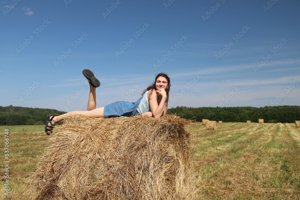 girl resting in a field on a haystack girl resting in a field on a haystack