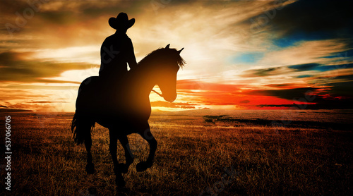 Cowboy on horseback in the prairie at sunset