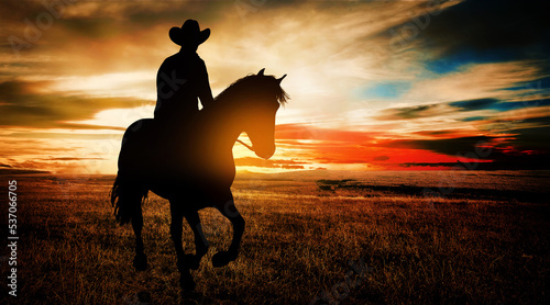 Cowboy on horseback in the prairie at sunset photo