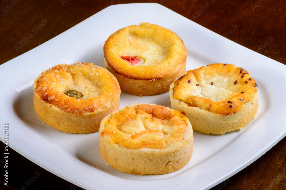 Mini quiches snacks of assorted flavors on a white plate. Mini quiches snacks of assorted flavors on a white plate.
