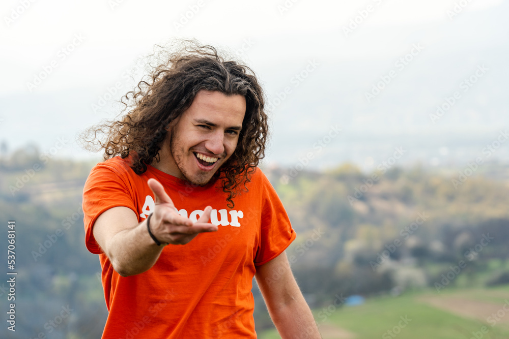 Fototapeta premium Young man laughs and fools on top of the mountain