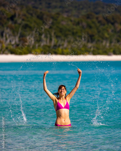 A beautiful girl in a bikini enjoys a dip in the turquoise water on whitehaven beach  relaxing on paradise beaches on whitsunday islands  queensland  australia