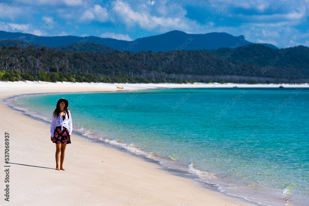 beautiful girl in dress and shirt and hat walks on paradise beach with white sand and turquoise water; walk on whitehaven beach on whitsunday island in queensland; paradise beaches of australia; sunny beautiful girl in dress and shirt and hat walks on paradise beach with white sand and turquoise water; walk on whitehaven beach on whitsunday island in queensland; paradise beaches of australia; sunny