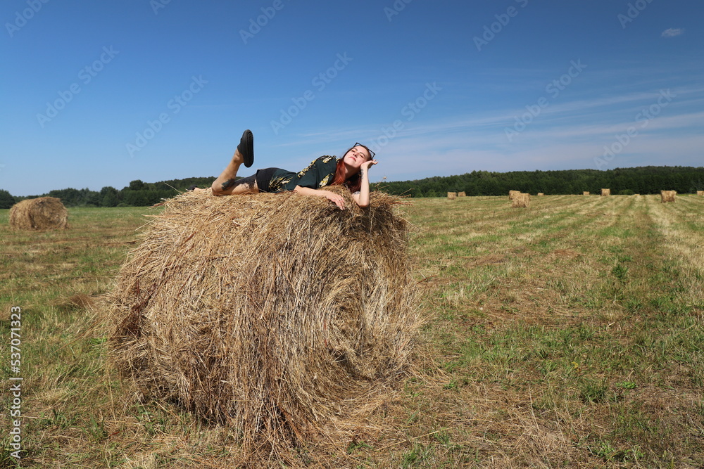 girl resting in a field on a haystack girl resting in a field on a haystack