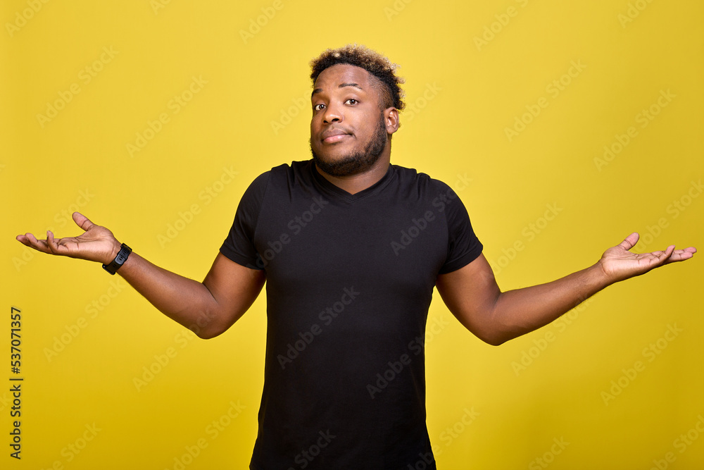 Cute fashionable AfricanAmerican spread his arms apart in surprise