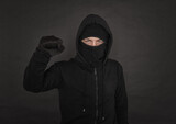 Man in the black hoody with hood wearing balaclava mask with fist up