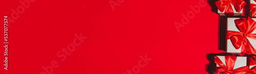 Gorgeous festive Christmas banner or header, holiday presents on red background. Christmas gift boxes on red. Holiday season, New Year. Copy space for text.