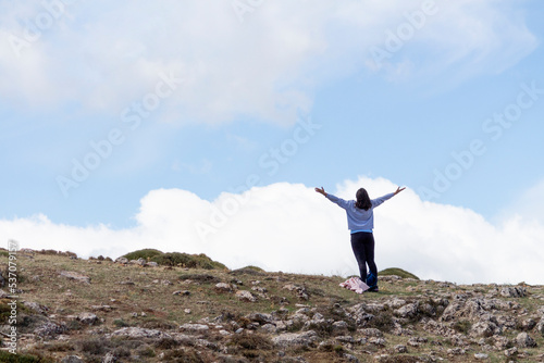 Mujer levantando los brazos hacia el cielo en un paisaje rocoso de montaña