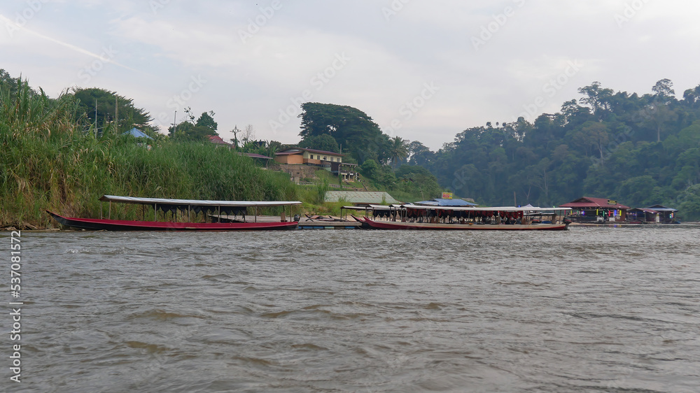 Obraz premium Boats and houses along the riverbank in the jungle rainforest, Taman Negara National Park, Malaysia