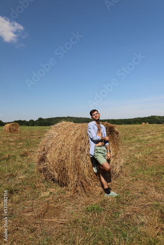 guy resting in a field on a haystack © DARYA KAUFMAN