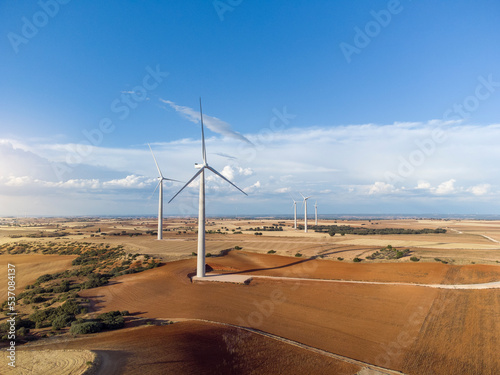 Aerial photograph of a field of windmills in a plowed crop field at sunset