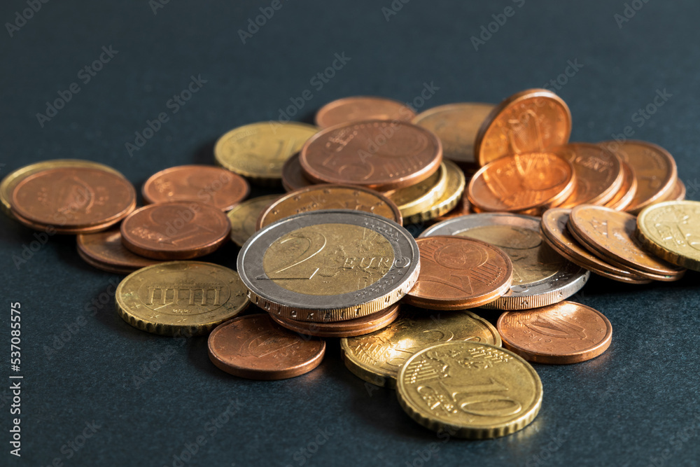 Euro coins spilled on the table. Euro coins, cents on black background. Soft focus Euro coins spilled on the table. Euro coins, cents on black background. Soft focus