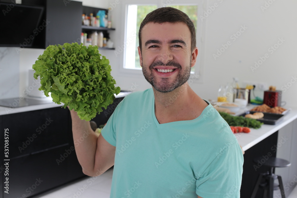 Man holding a delicious looking lettuce in the kitchen Man holding a delicious looking lettuce in the kitchen