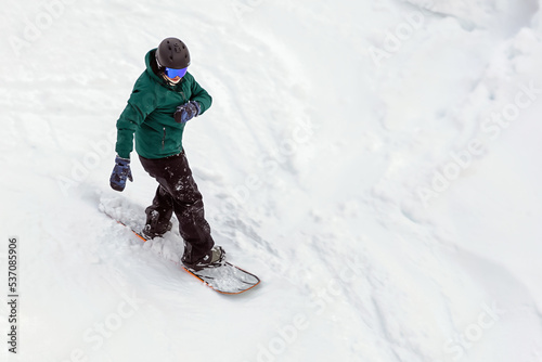 snowboarder in equipment descends mountain slope, active recreation in winter, extreme winter recreation