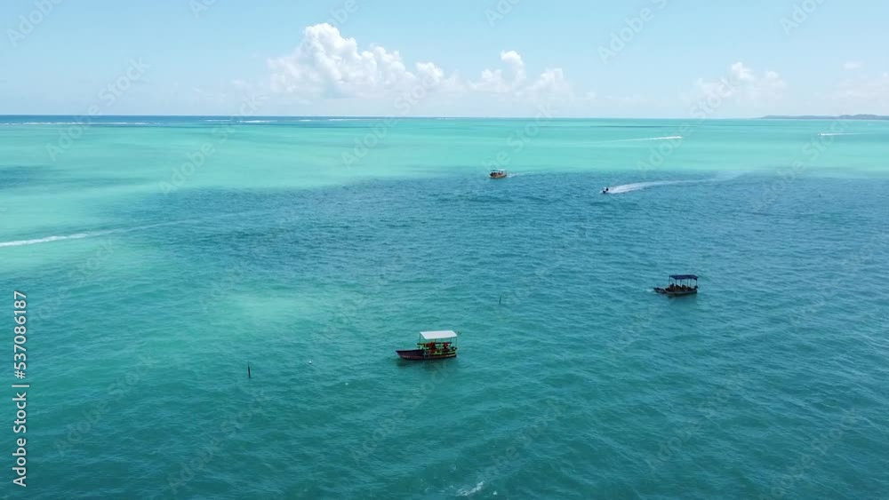 A blue sea with boats on Praia de Antunes beach in Brazil