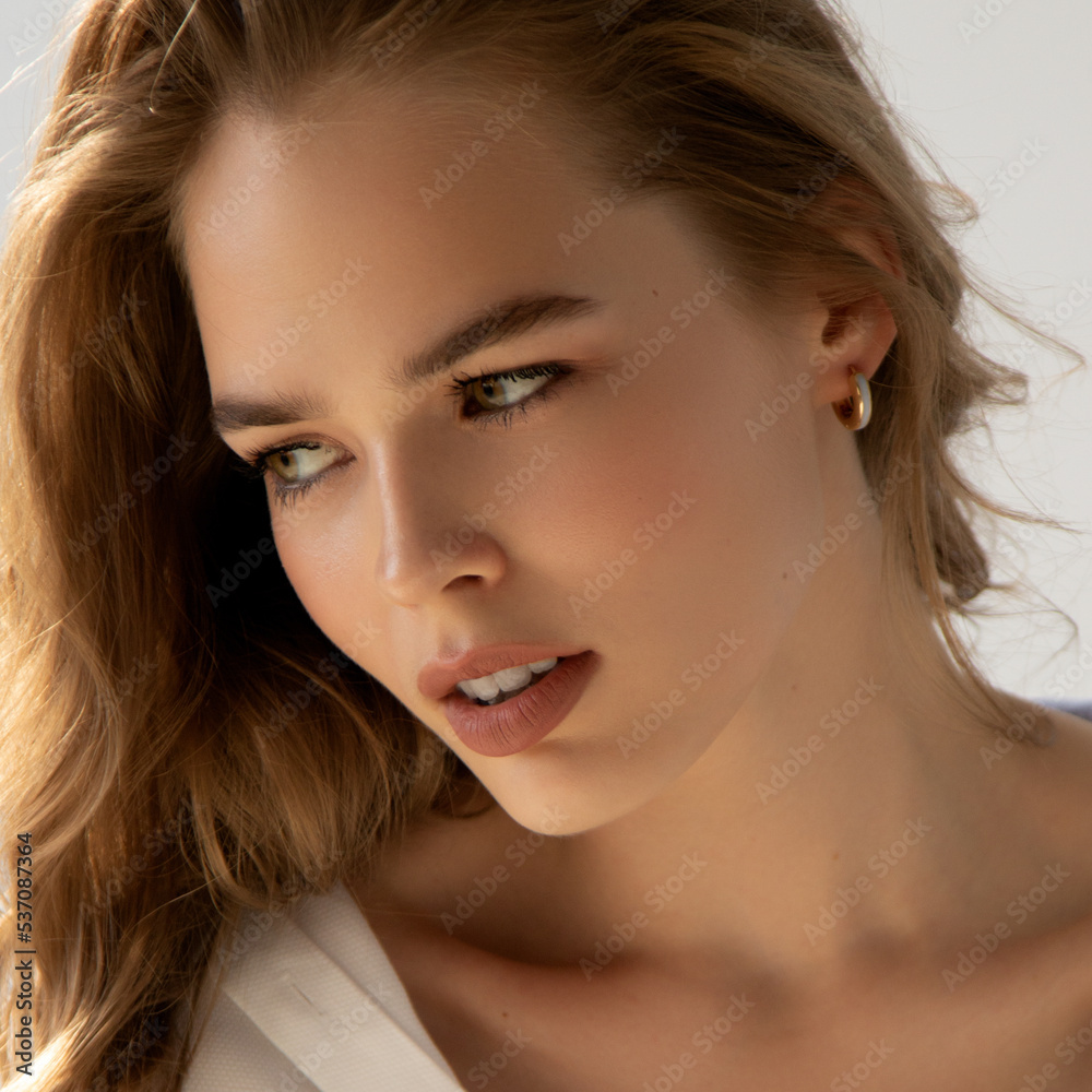A glamorous beautiful fashion girl in a white shirt. Natural photography. Fashion and beauty. Beauty girl with wavy hair poses in the studio A glamorous beautiful fashion girl in a white shirt. Natural photography. Fashion and beauty. Beauty girl with wavy hair poses in the studio