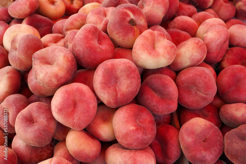 peaches on a market stall. flat nectarines as food background.