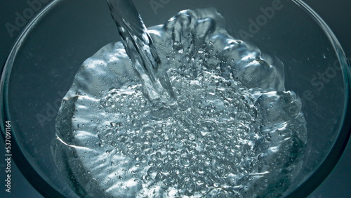 Sparkling aqua pouring glass top view closeup. Mineral drink filling glassware