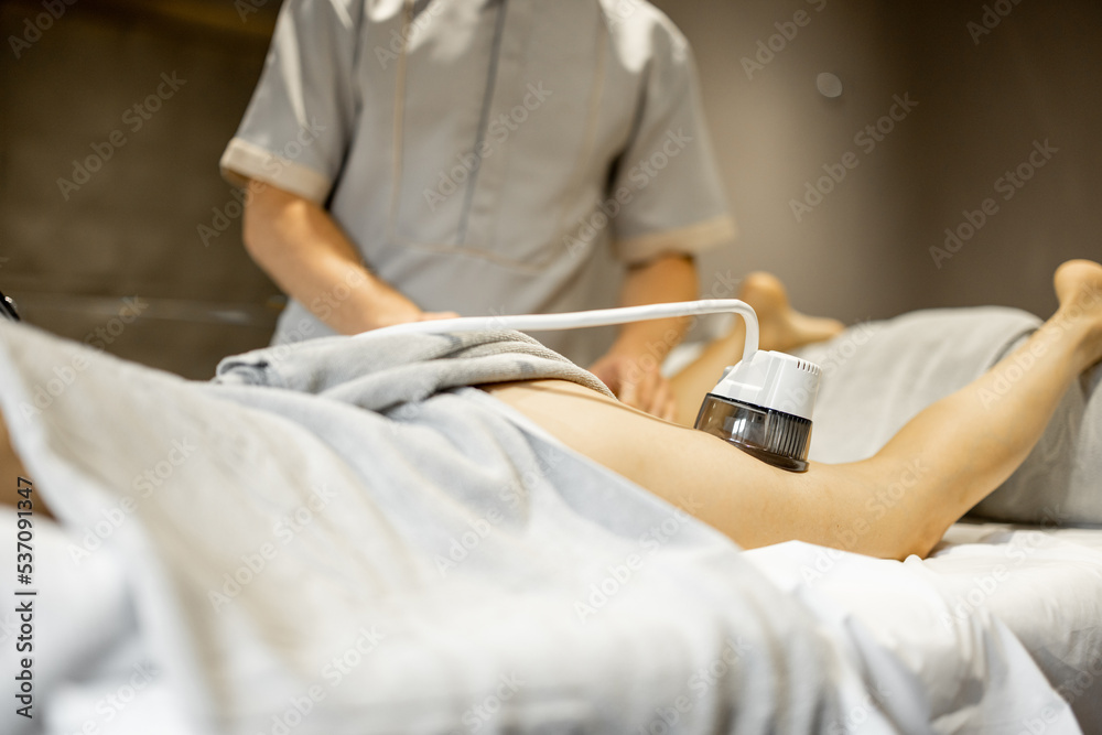 Applying vacuum roller massage to female leg using a special nozzle at beauty medical center. Concept of modern medical procedures for beauty