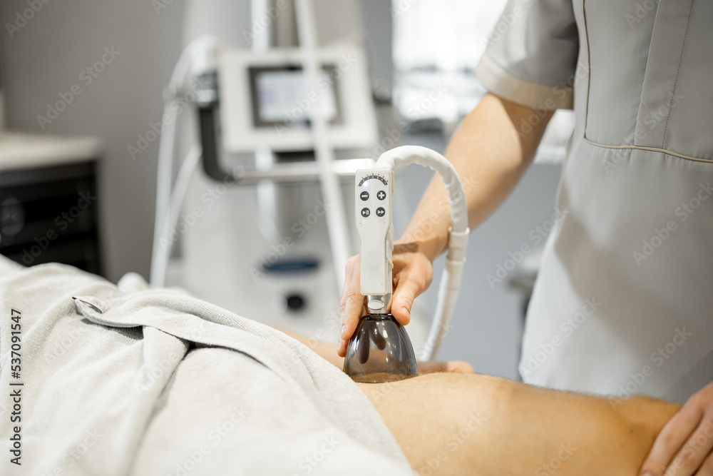 Applying vacuum roller massage on male leg using a special nozzle at beauty medical center, close-up. Concept of modern medical procedures for beauty Applying vacuum roller massage on male leg using a special nozzle at beauty medical center, close-up. Concept of modern medical procedures for beauty