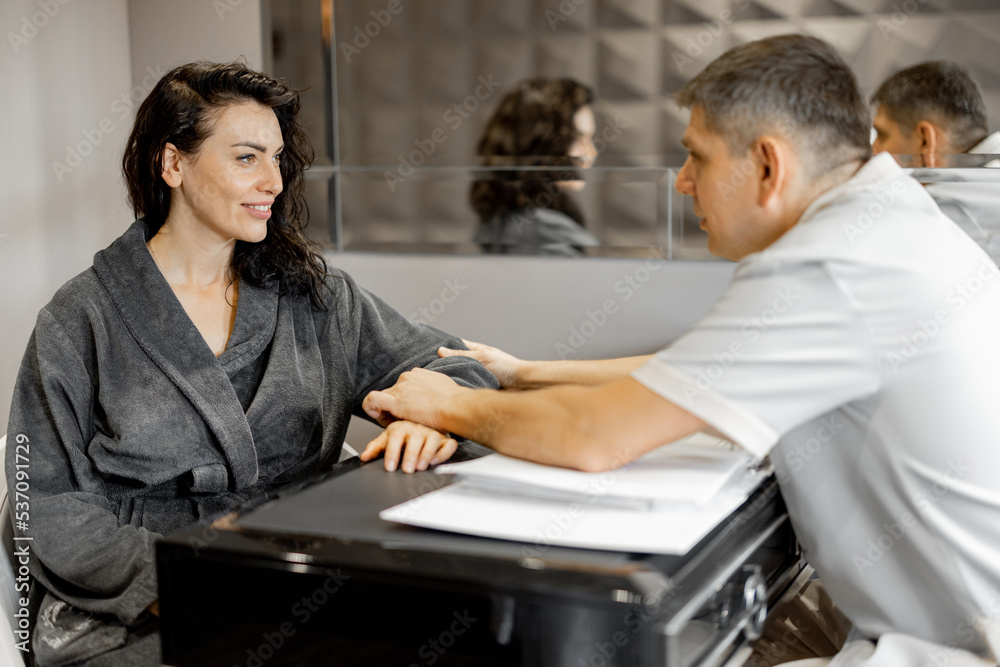 Woman in a bathrobe on appointment with senior therapist in luxury medical spa salon. Consultation with a doctor before beauty procedures Woman in a bathrobe on appointment with senior therapist in luxury medical spa salon. Consultation with a doctor before beauty procedures